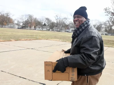 Offutt Giving Thanks smiling man with box of food